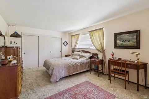 a bedroom with a bed table chair and a window
