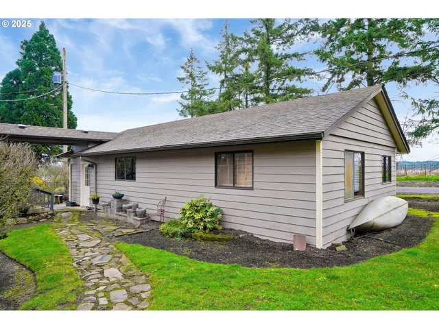 a view of a white house with a yard potted plants and a table