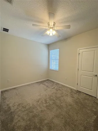 an empty room with windows and fan