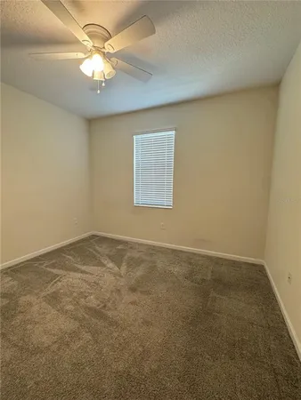 an empty room with a chandelier fan and windows