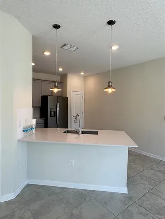 a large kitchen with a refrigerator a sink and a large mirror