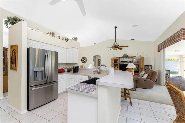 a kitchen with stainless steel appliances kitchen island granite countertop a refrigerator oven a sink dishwasher a dining table and chairs with wooden floor