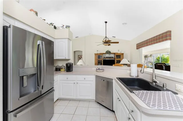 a kitchen with a sink a stove a refrigerator and white cabinets