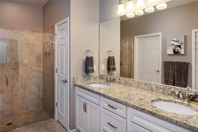 a bathroom with a granite countertop double vanity sink shower and a mirror