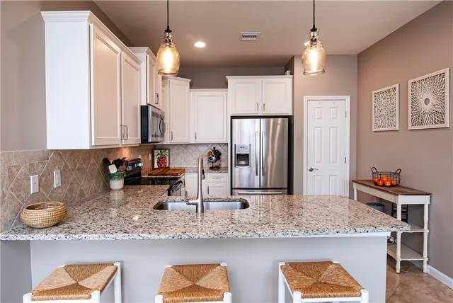 a kitchen with kitchen island granite countertop a sink a center island stainless steel appliances and cabinets
