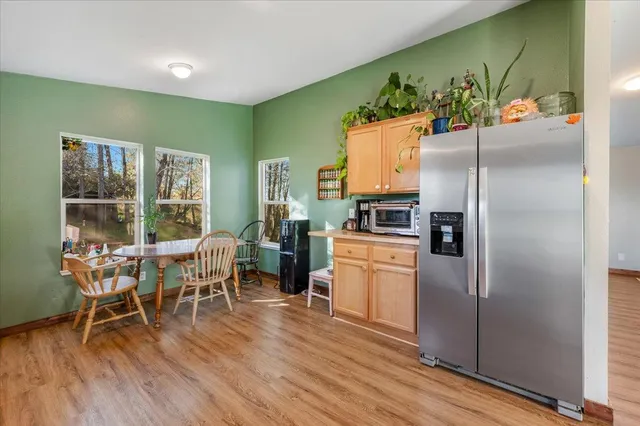 a view of a kitchen with kitchen island a large window cabinets a sink and stainless steel appliances