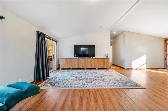 a living room with kitchen view and a flat screen tv