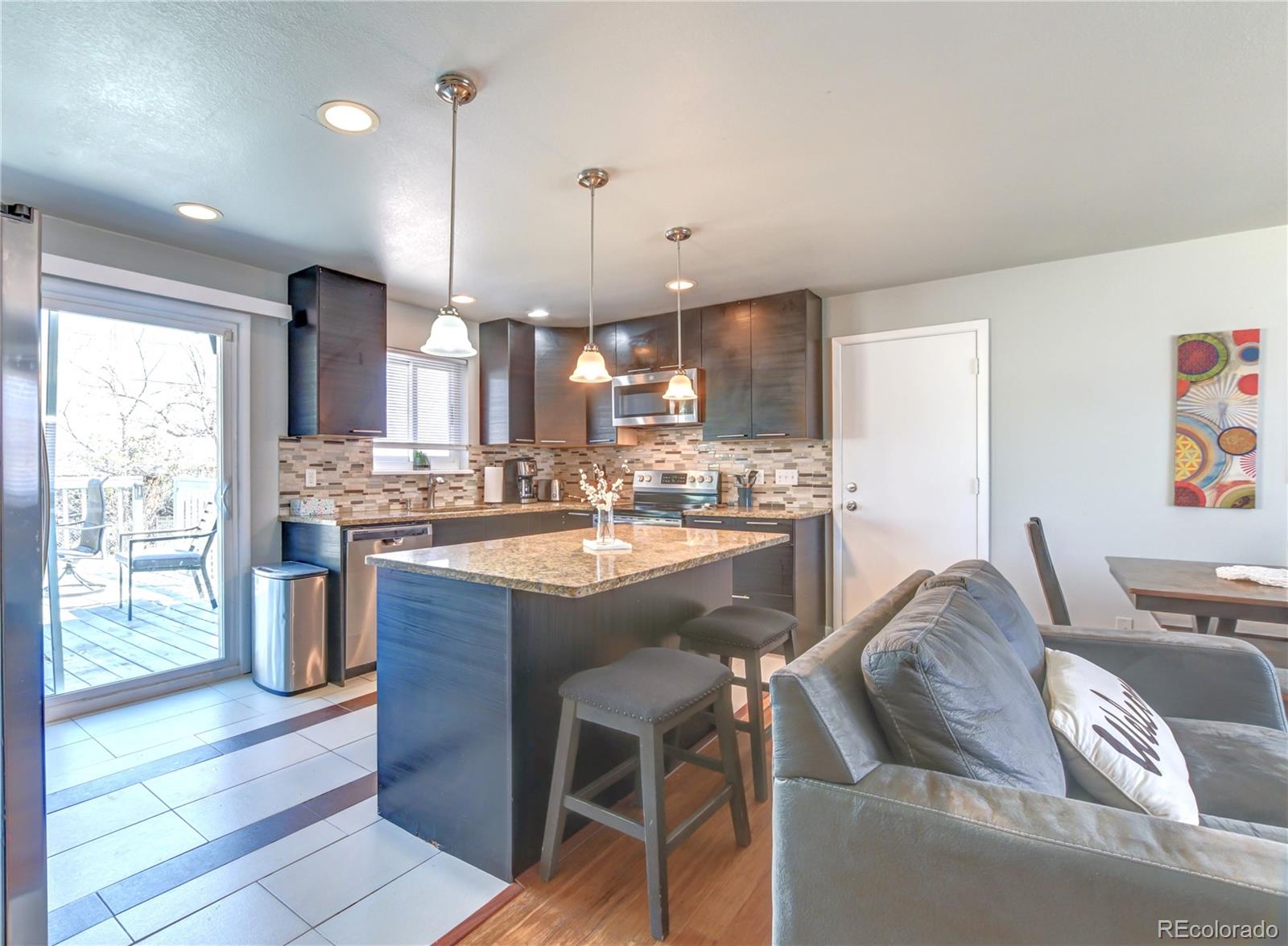 2361 West 57th Avenue Denver, CO 80221 - Photo 2 of 15 a kitchen with stainless steel appliances granite countertop a sink a stove a refrigerator cabinets and chairs