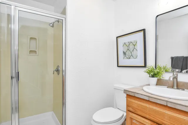a bathroom with a granite countertop sink toilet and a mirror
