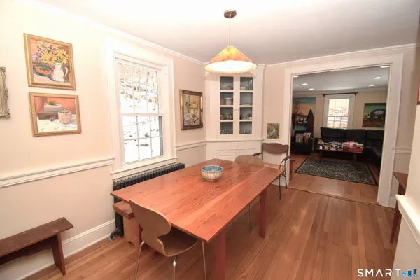 a dining room with wooden floor and large windows