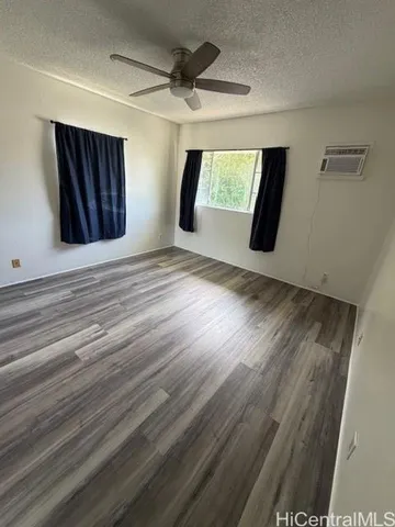 a view of an empty room with wooden floor and window