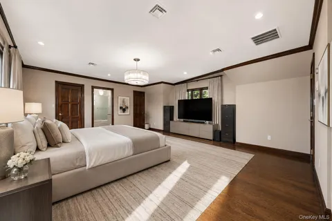 a spacious bedroom with a large bed a flat tv screen and a dresser