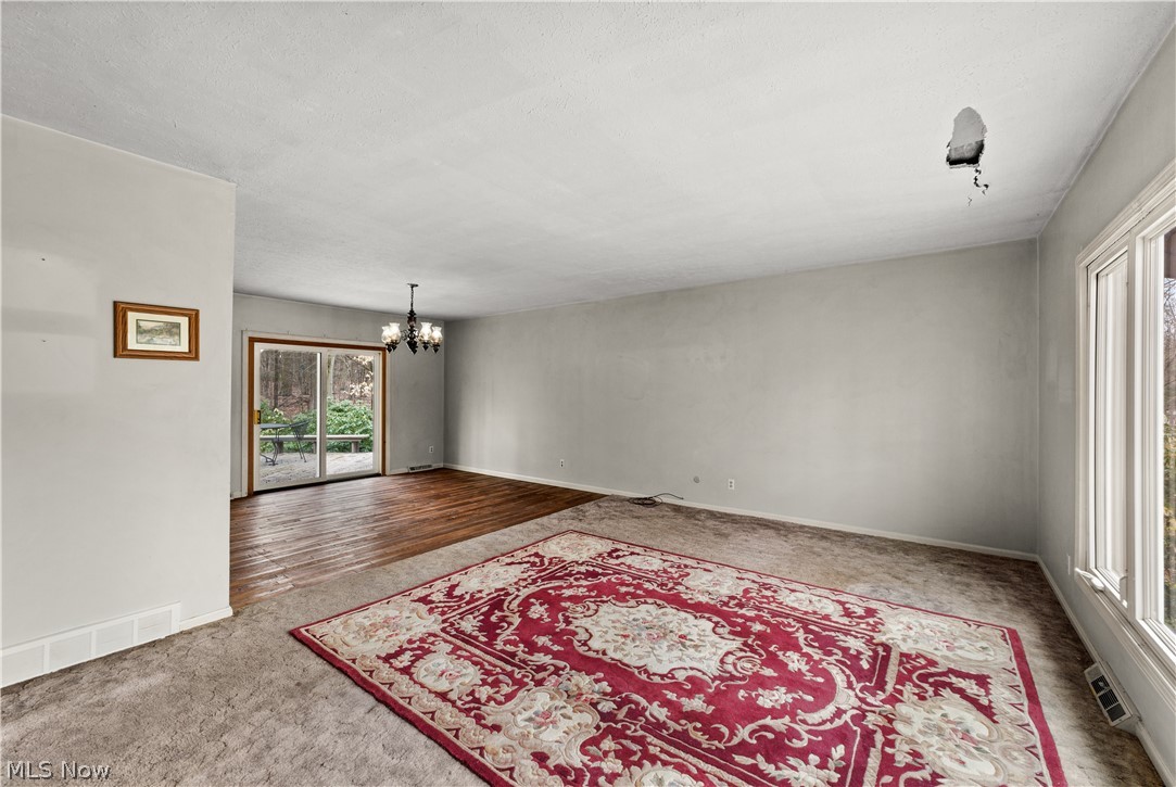 18763 Sharon Road Chagrin Falls, OH 44023 - Photo 17 of 37 Carpeted empty room with a chandelier in adjacent dining room