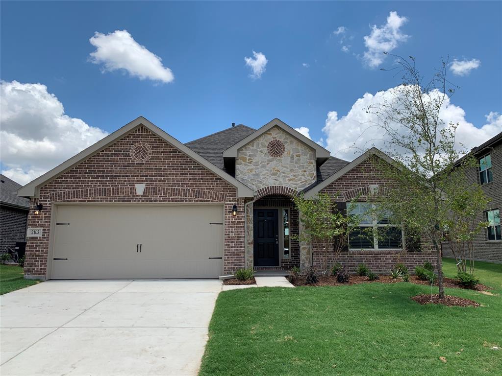 View of front of property featuring brick siding, a garage, a front yard, and concrete driveway
