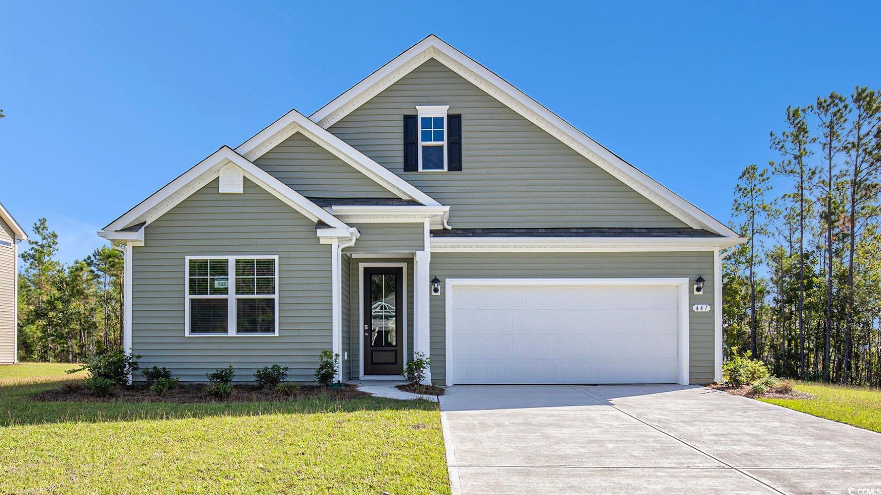 Traditional home featuring a front yard, driveway, and a garage