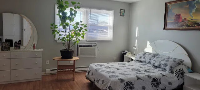 a bedroom with a bed table chair and a potted plant