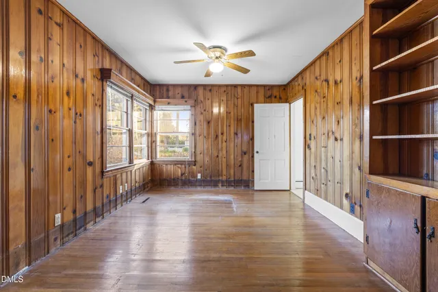 a view of a livingroom with wooden floor a ceiling fan and a kitchen space