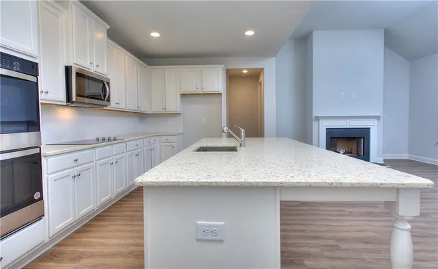 a kitchen with stainless steel appliances granite countertop a sink dishwasher a stove and a microwave oven with wooden floor