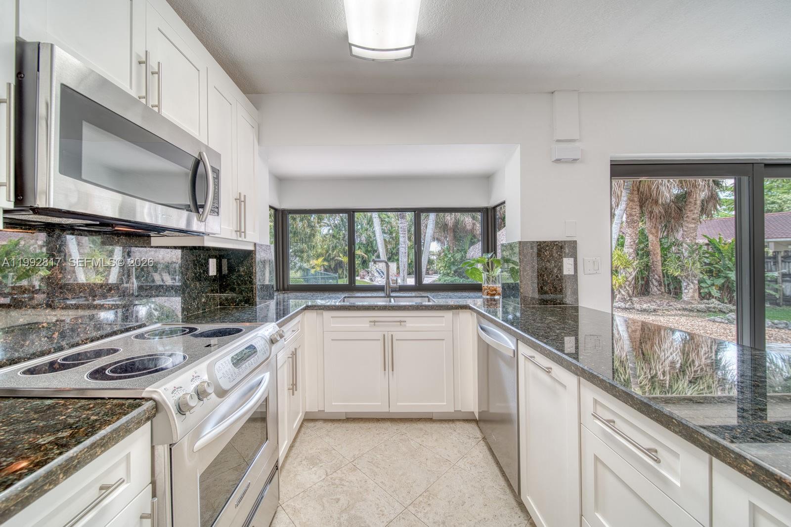 7320 Southwest 100th Court Miami, FL 33173 - Photo 11 of 36 a kitchen with stainless steel appliances granite countertop a stove a sink and a microwave