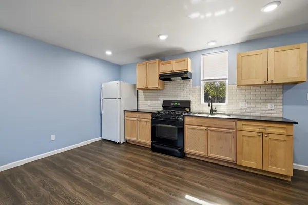 a kitchen with granite countertop a refrigerator stove top oven and sink