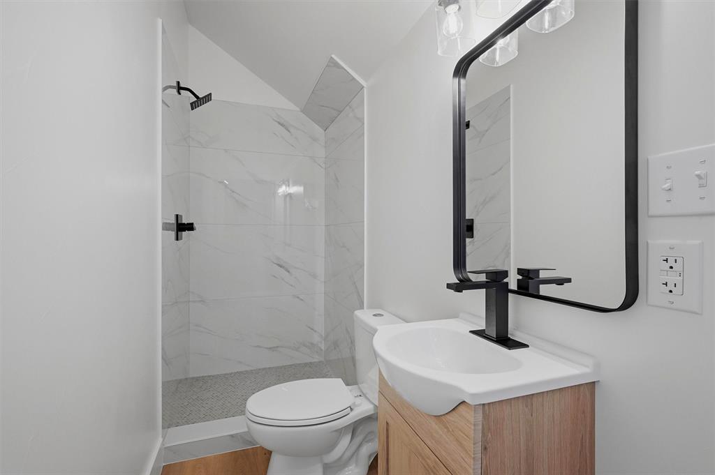 410 Arkansas Road Sadler, TX 76264 - Photo 29 of 40 Bathroom featuring a walk-in shower with large format white tile, a dark-finish rainfall showerhead, and dark-finish fixtures