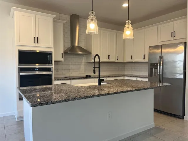 a kitchen with stainless steel appliances granite countertop a sink a refrigerator and a granite counter tops