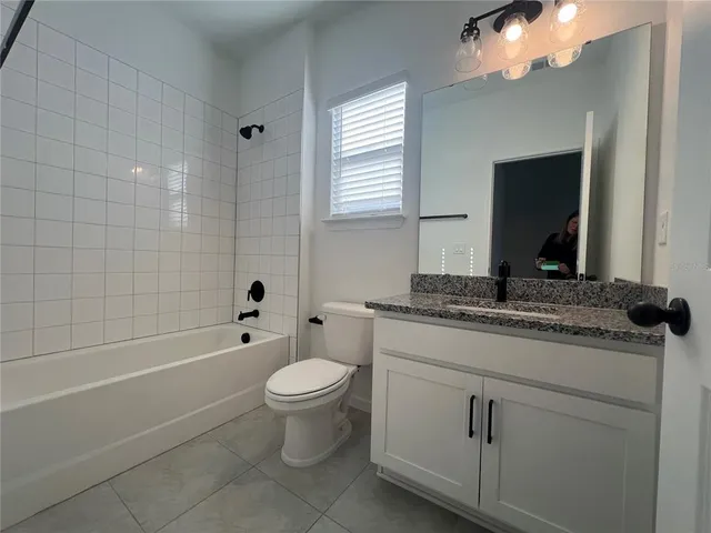 a bathroom with a granite countertop toilet a sink and bathtub