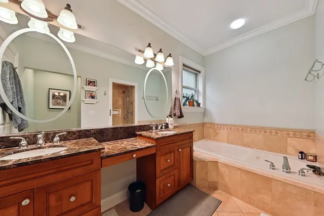 a bathroom with a sink double vanity granite tub and a mirror