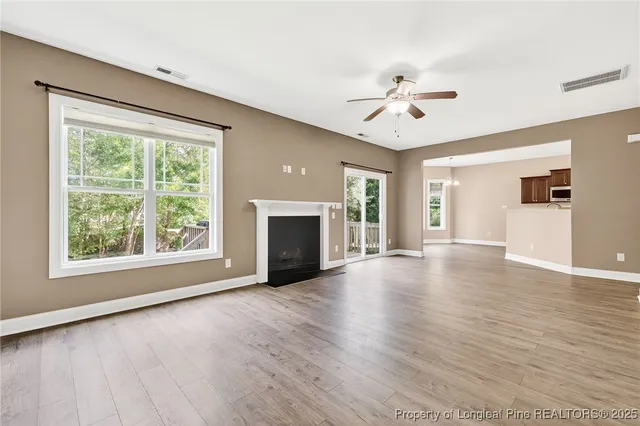 a view of an empty room with window and wooden floor