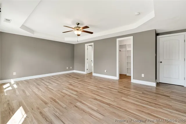 a view of empty room with wooden floor and ceiling fan