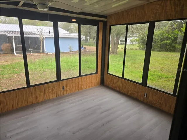 a view of an empty room with wooden floor and windows