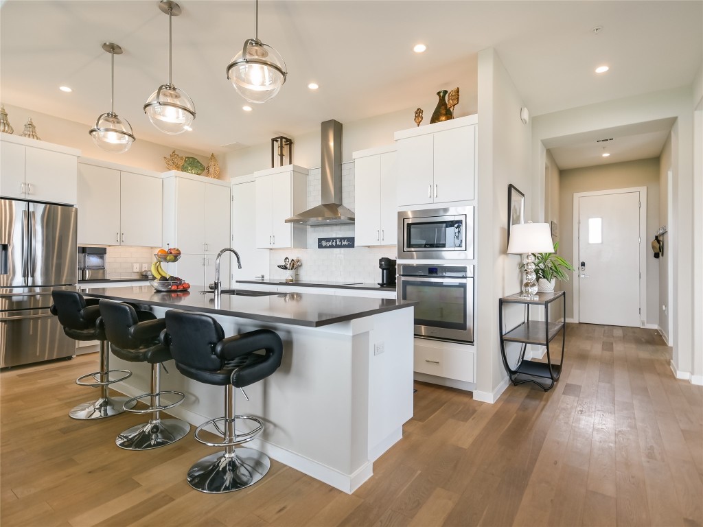 5921 Hiline Road, Unit 1501 Austin, TX 78734 - Photo 6 of 39 a kitchen with stainless steel appliances granite countertop a refrigerator oven a stove a sink a dining table and chairs with wooden floor