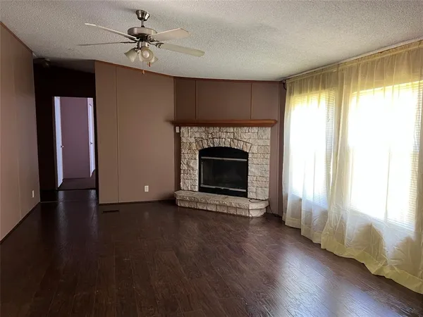 an empty room with wooden floor fireplace and windows