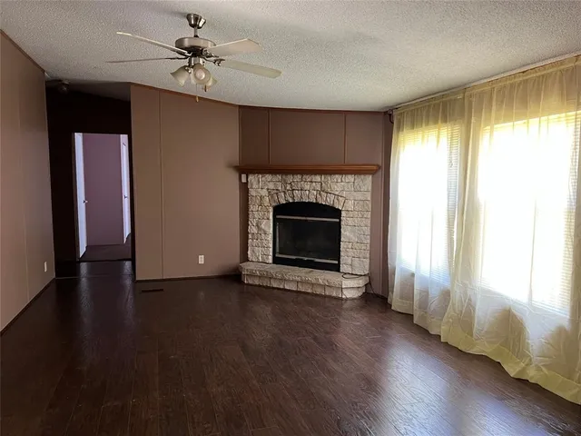 an empty room with wooden floor fireplace and windows