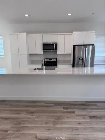 a kitchen with stainless steel appliances cabinets and wooden floor