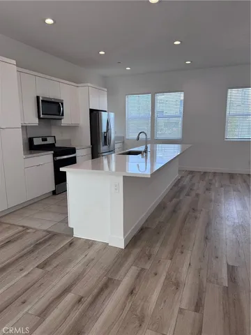 a large white kitchen with wooden floor and a refrigerator