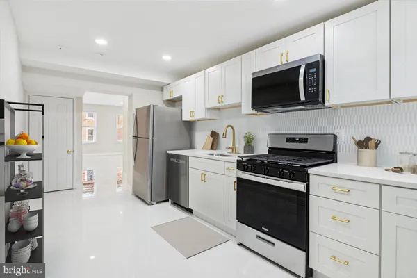 a kitchen with stainless steel appliances a white stove top oven a sink dishwasher and a refrigerator with wooden floor