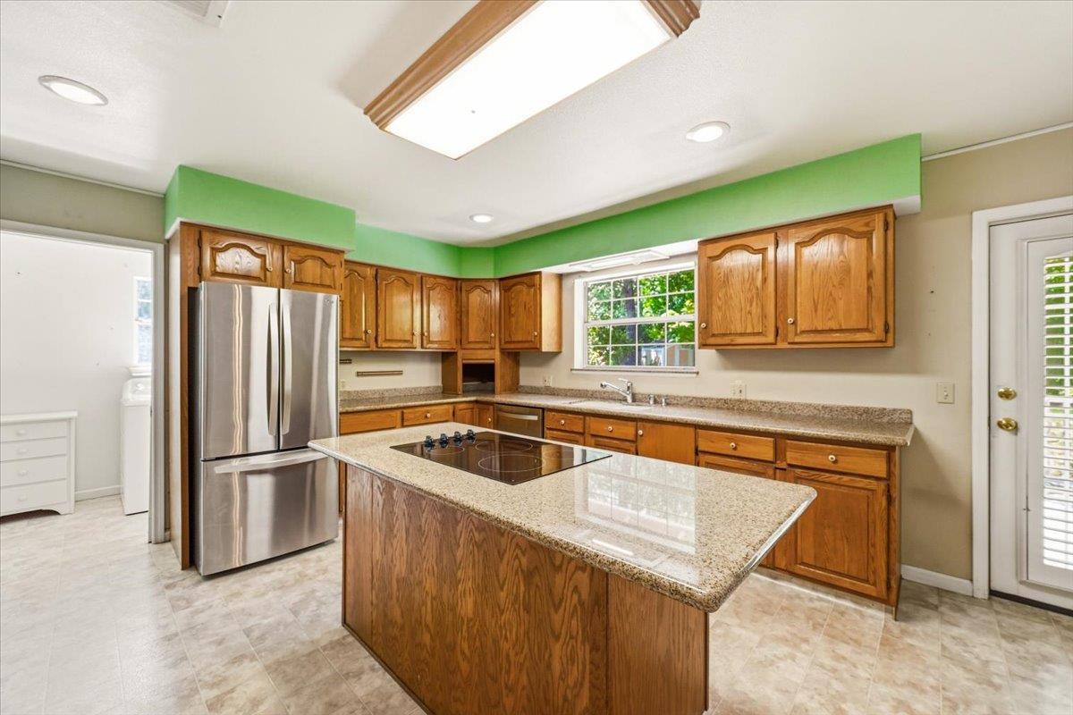 12600 Friar Tuck Road Grass Valley, CA 95949 - Photo 26 of 56 a kitchen with kitchen island a large window cabinets and stainless steel appliances