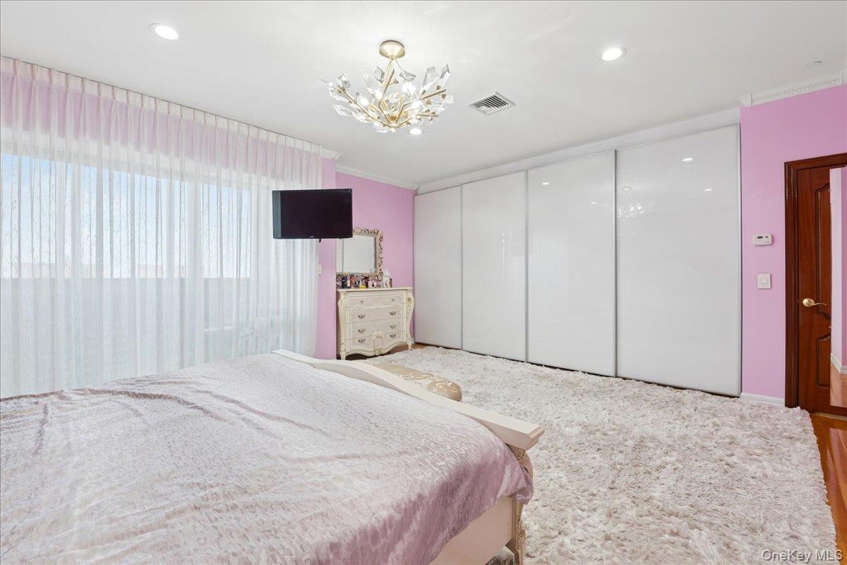 99-31 66th Avenue, Unit 7B Queens, NY 11374 - Photo 14 of 26 a spacious bedroom with a bed and a chandelier