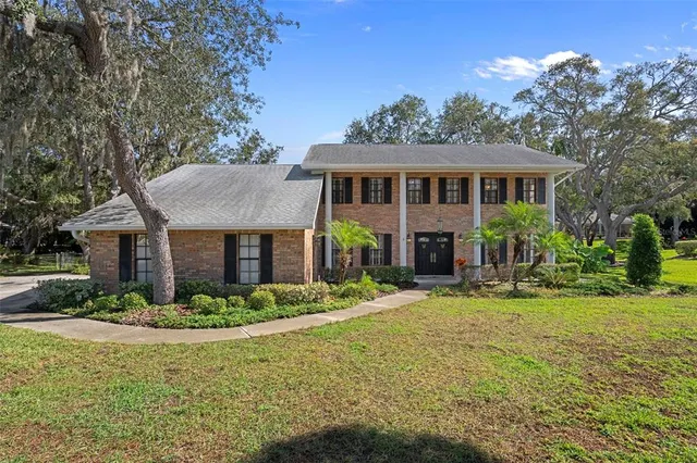 a front view of house with yard and trees in the background