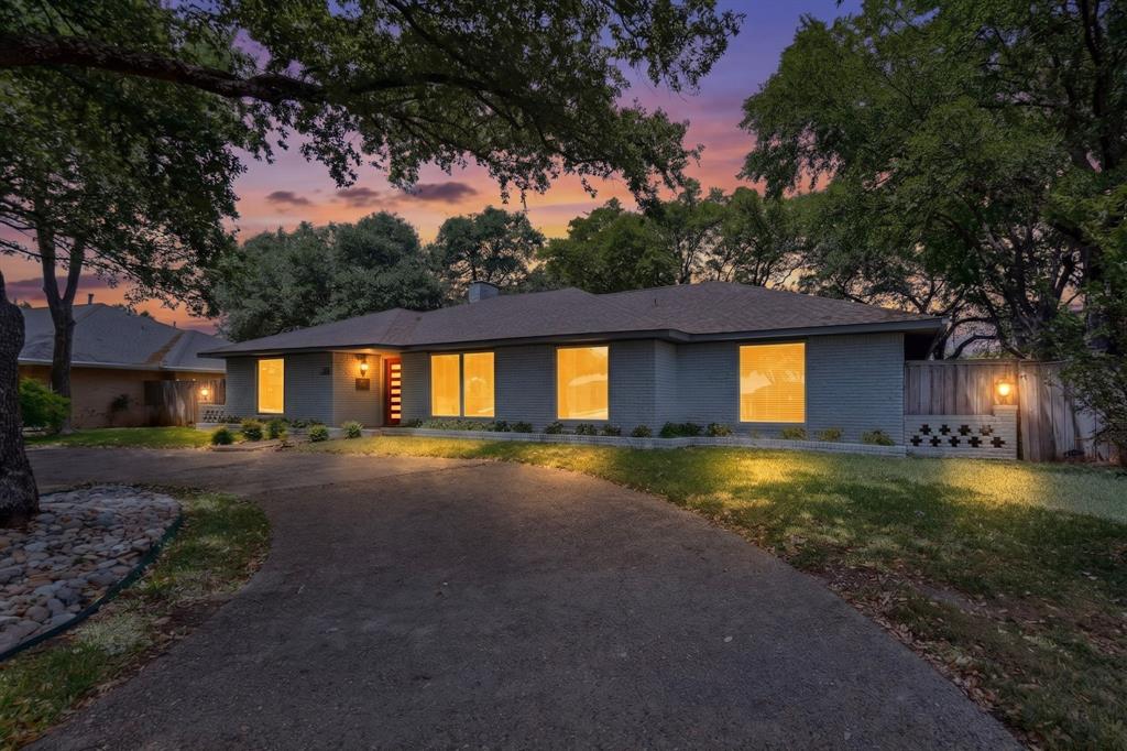 7631 Meadow Road Dallas, TX 75230 - Photo 1 of 40 A cozy house with a driveway surrounded by trees