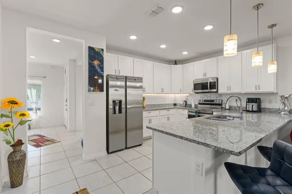 a kitchen with stainless steel appliances granite countertop a sink refrigerator and cabinets