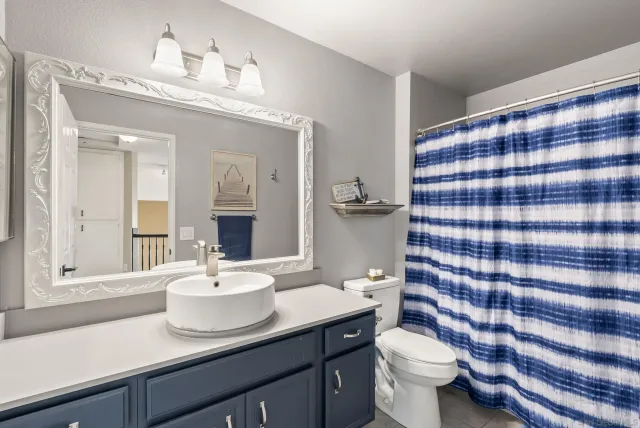 a bathroom with a sink a toilet a mirror and shower curtain