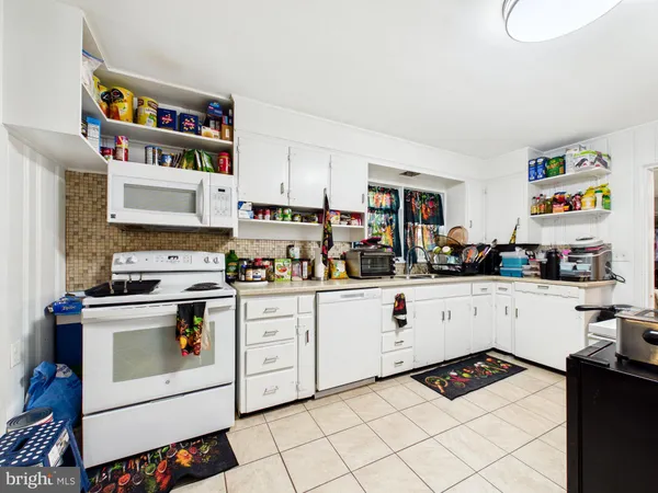 a white kitchen with stainless steel appliances granite countertop a stove and a sink