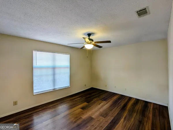 a view of empty room with wooden floor and fan