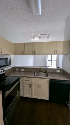 a kitchen with stainless steel appliances a sink dishwasher a stove and white cabinets