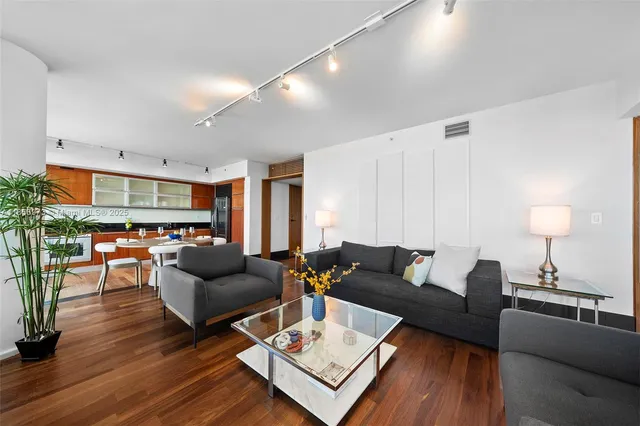 a living room with furniture large windows and wooden floor