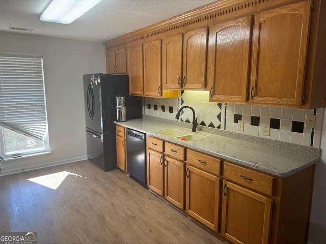 a kitchen with stainless steel appliances granite countertop a sink a stove and a refrigerator with wooden floor