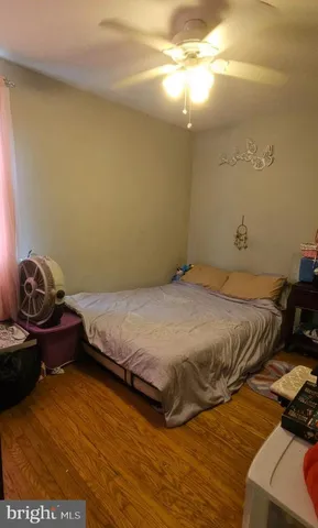 a bedroom with a bed and dresser with wooden floor