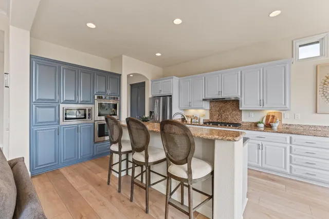 a kitchen with stainless steel appliances kitchen island granite countertop a stove a sink a refrigerator with a dining table and chairs